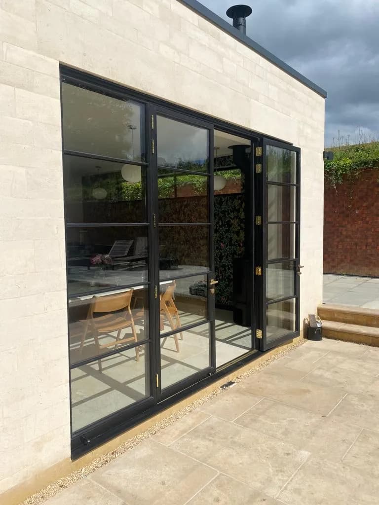 Contemporary extension glazing reflecting trees and sky within the Cotswolds AONB landscape