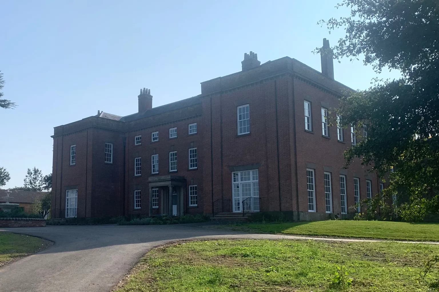 A Georgian red-brick country house with original timber sash windows, seen from its drive