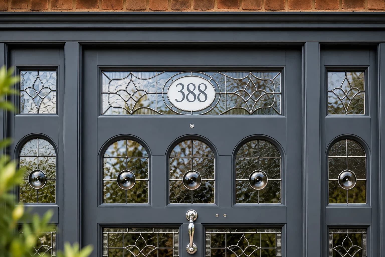 Close view of the fanlight and arched glazing heads of a bespoke entrance door, leaded and bevelled glass in deep grey Accoya