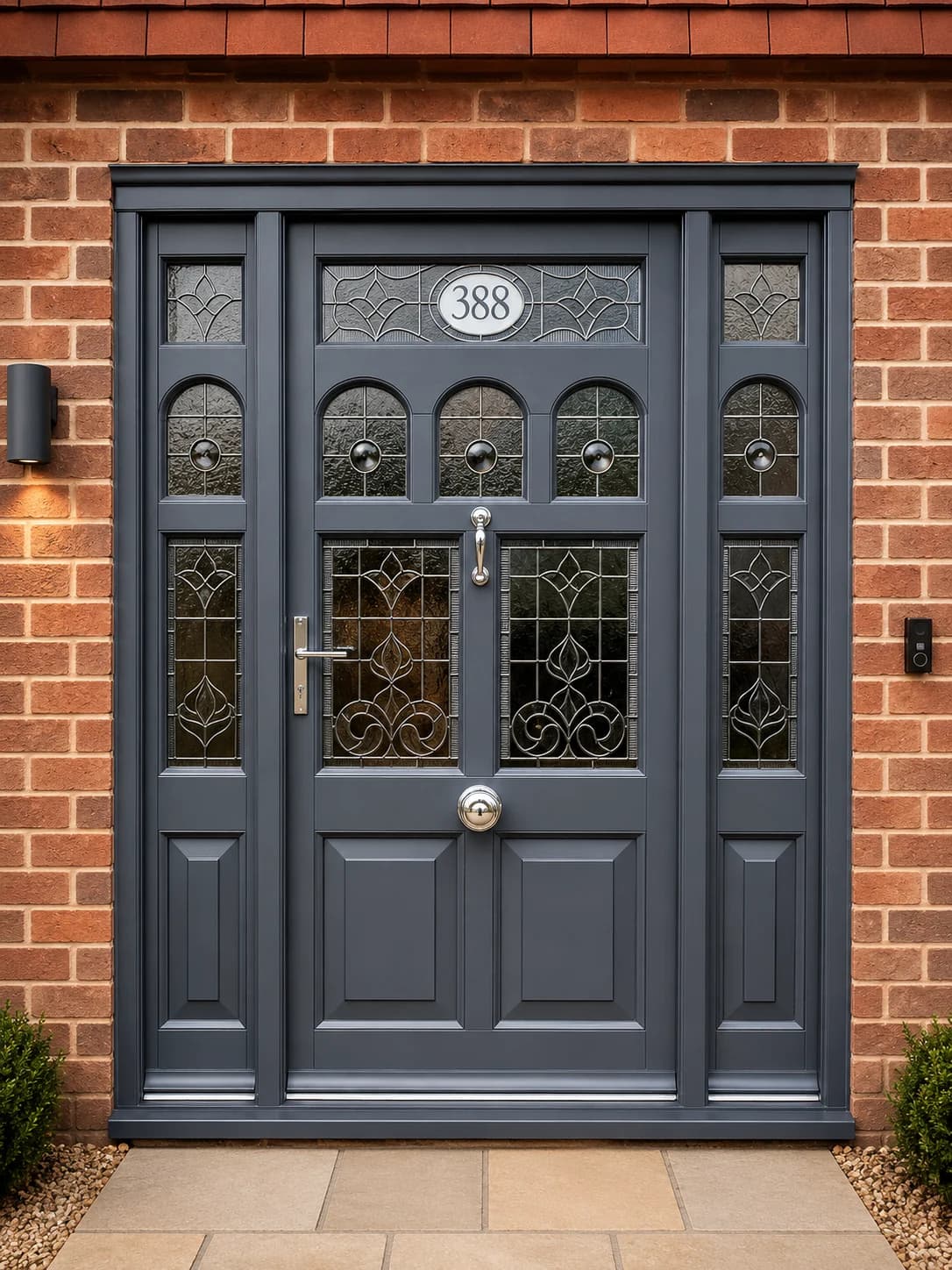 The complete entrance assembly square on — door, flanking sidelights and fanlight in deep grey Accoya with leaded and bevelled glazing and polished chrome ironmongery