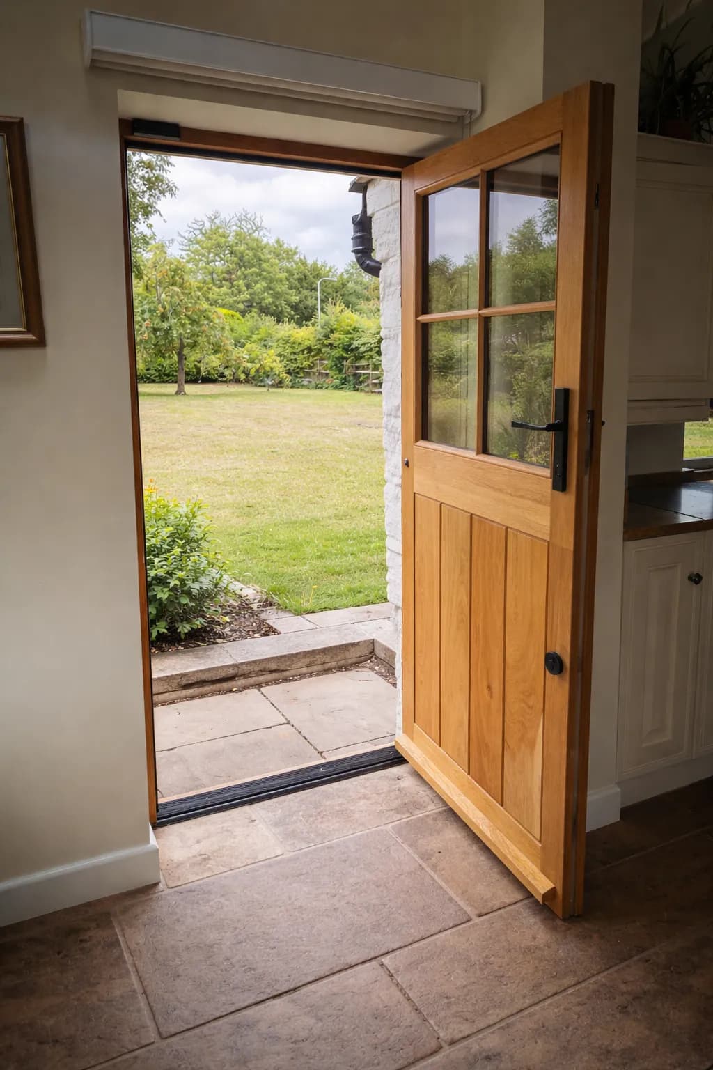 Oak stable door open from the kitchen onto the garden, six-pane glazed upper leaf and boarded lower leaf on beeswax-finished ironmongery