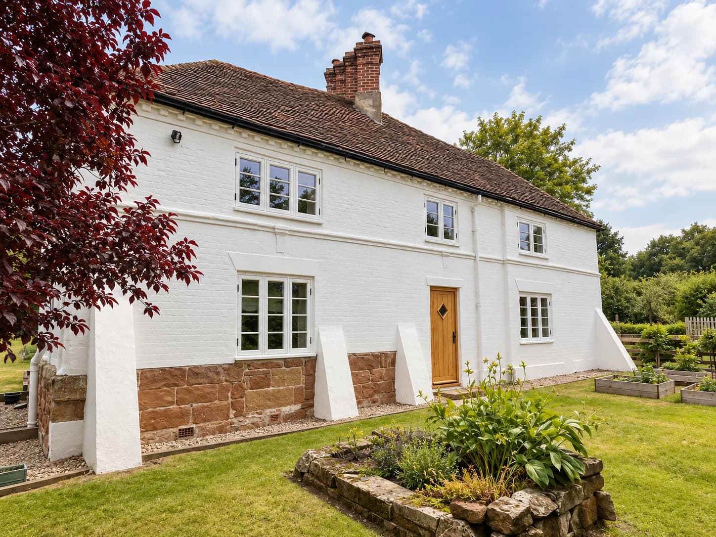 Front elevation showing the oak front door flanked by white-painted Accoya flush casement windows above a red sandstone plinth