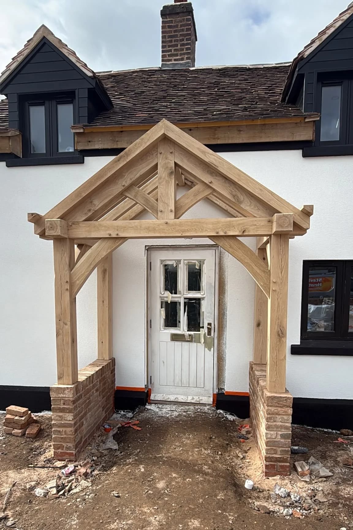 The green oak porch frame standing at the cottage before the ground was made up, the oak pale and freshly cut, brick piers newly built