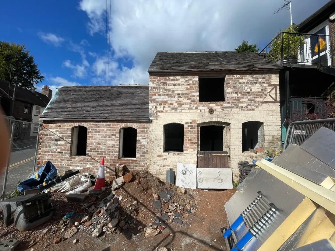 Before: the derelict brick building with empty window and door openings, scaffolding materials and rubble in front