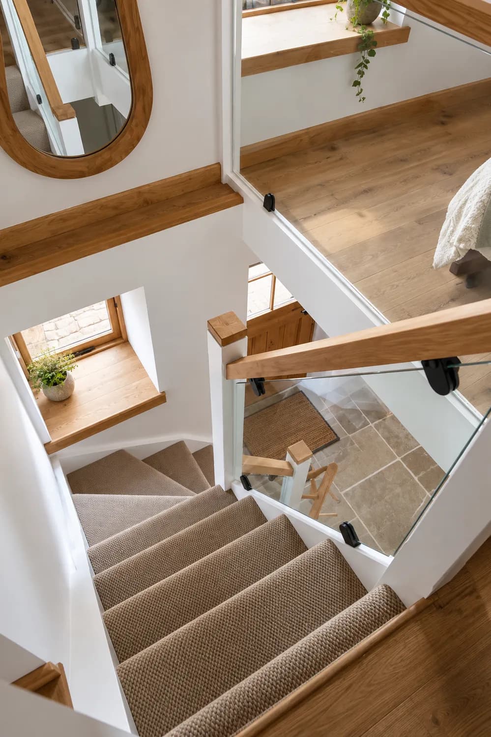Looking down the staircase from the landing, with an oak handrail, glass balustrade and oak window boards