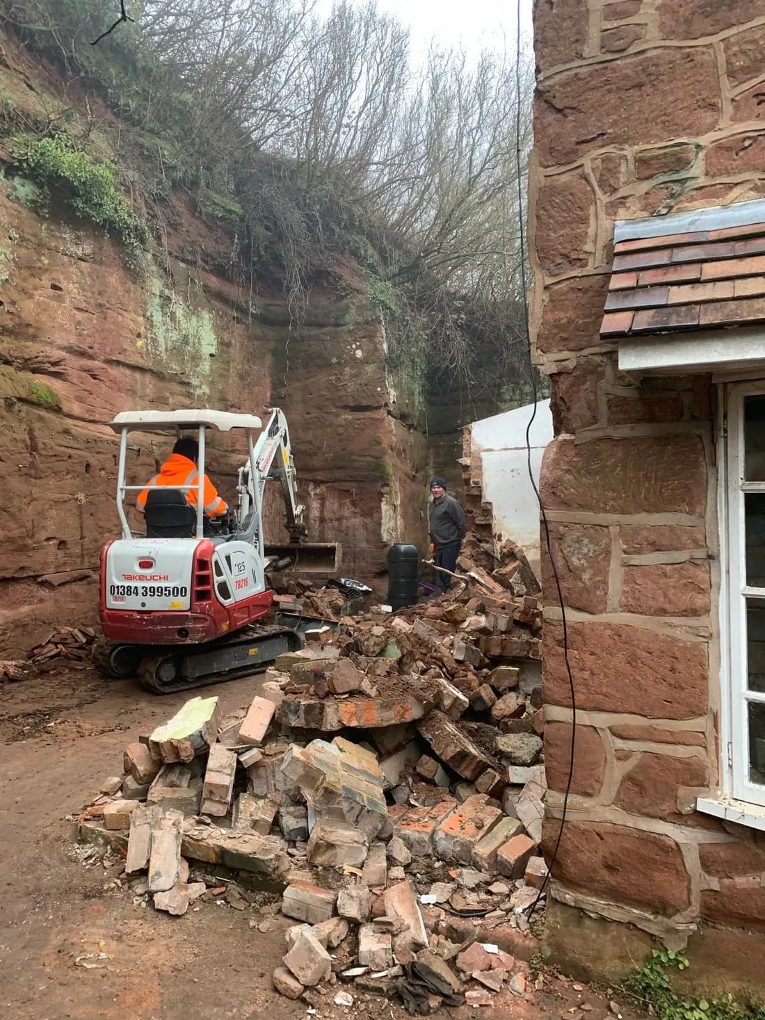 Mini digger among rubble in the sandstone cutting behind the cottage