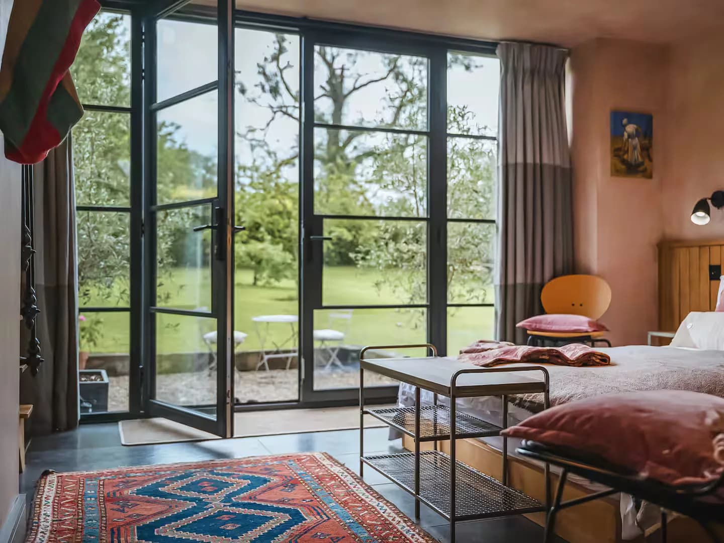 Bedroom in the converted barn with slim steel-look Accoya French doors open to the garden