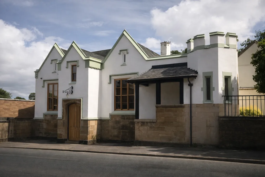 A rendered period property with a sandstone plinth, timber casement windows and an oak boarded door