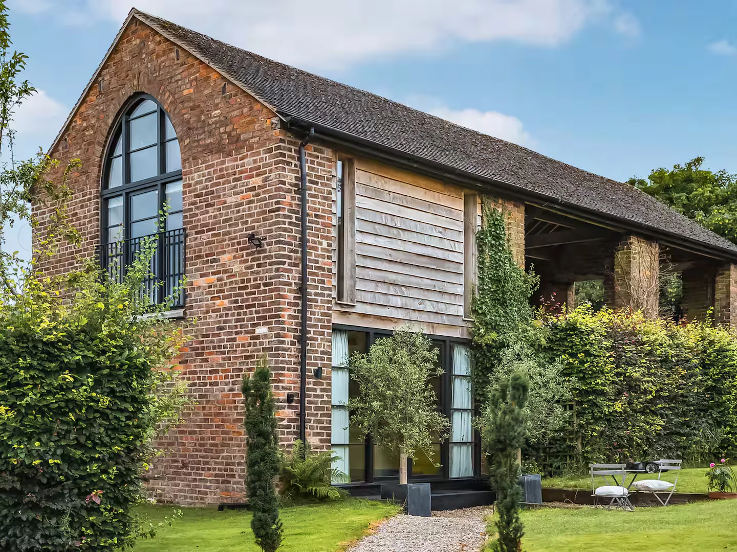 Converted brick barn near Tarporley with slim steel-look Accoya glazing and an arched glazed unit in the gable